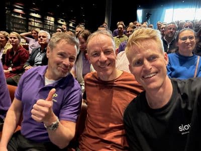 Mads Nissen wearing a Slowly shirt at the Puzzlepart 15-year anniversary celebration with former colleagues in an auditorium, 2023